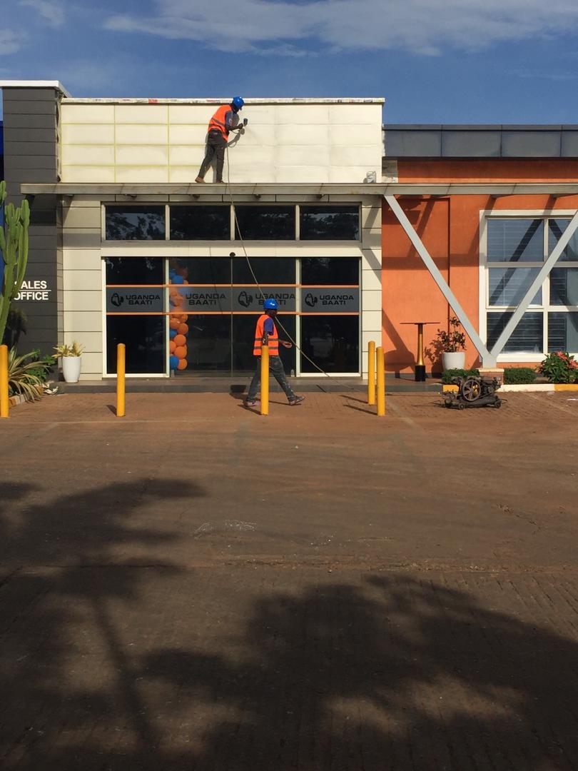 Painter finishing the upper fascia above the Uganda Baati sales office signage