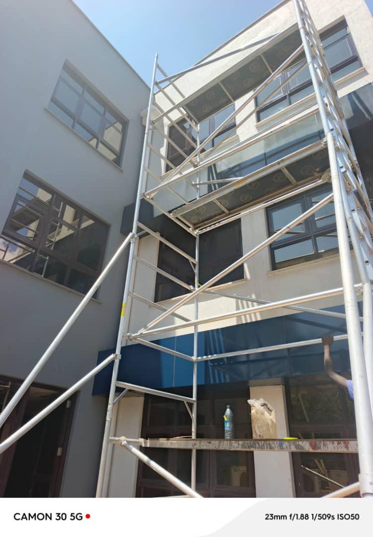 Aluminium tower scaffold set up against a grey office block for exterior repainting