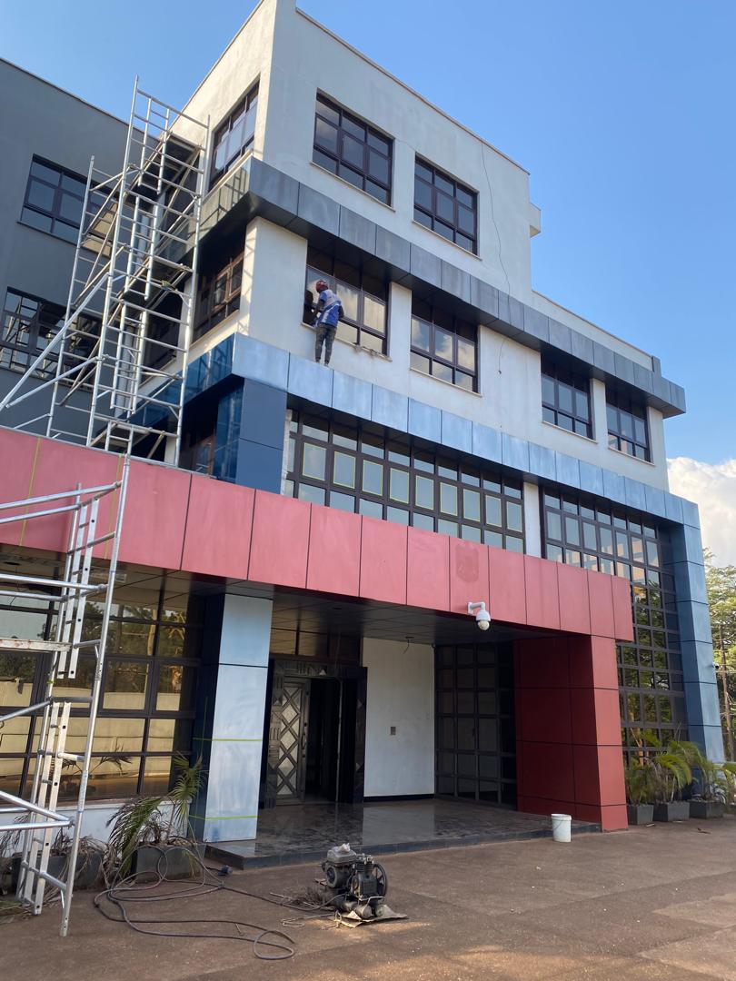 Painter on external scaffold repainting window surrounds on a multi-storey office block