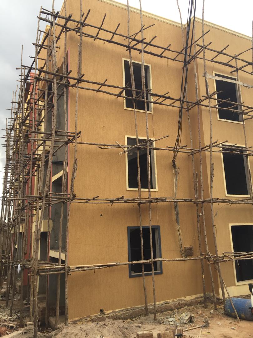 Timber scaffolding covering a tan-rendered commercial building under repaint