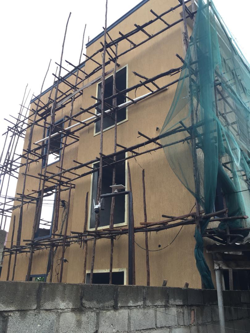 Multi-storey building wrapped in scaffold and safety netting during exterior painting