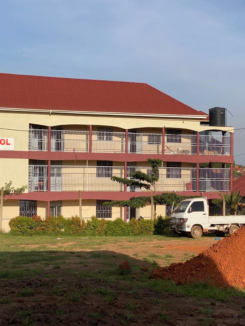 Institutional building exterior in cream with red roofline
