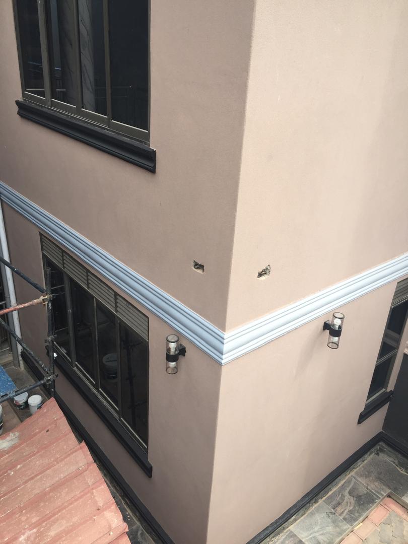 Corner detail of a mauve-toned residential exterior with grey trim banding