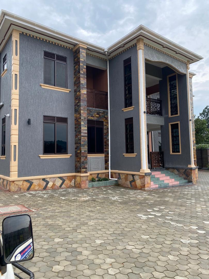 Two-storey residence in dark grey render with stone-clad pillars and pink tiled steps