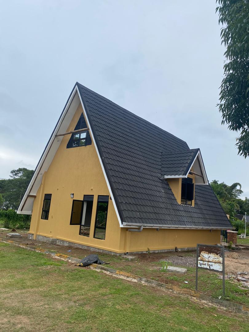 Yellow A-frame chalet exterior with dark tiled roof and dormer window, freshly rendered