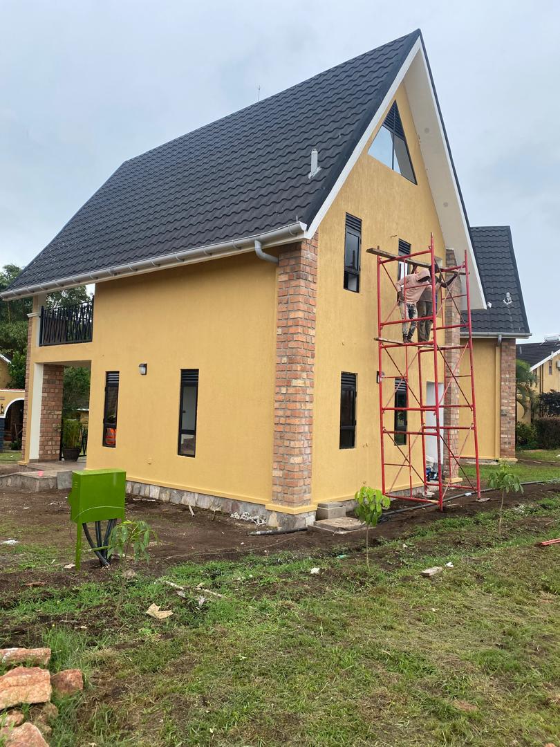 Twin-gable yellow residence exterior with dark tiled roofs and brick pillar trim