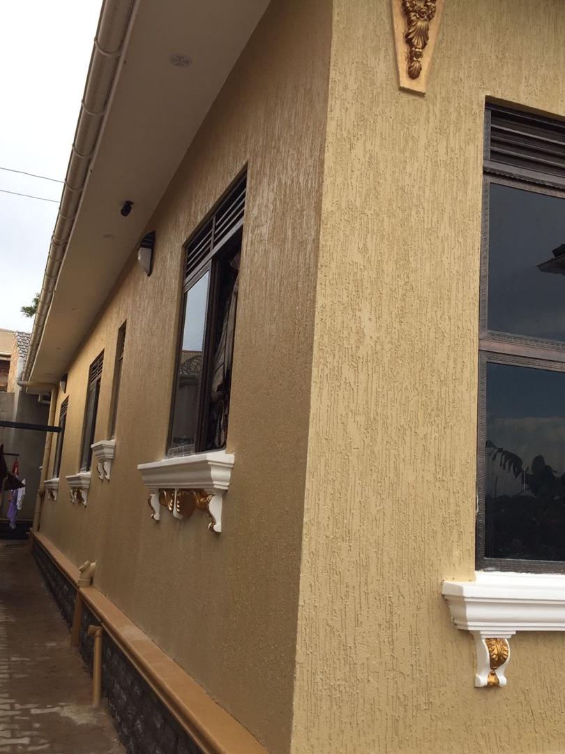 Close view of decorative gold and white window cornices on a rendered bungalow facade