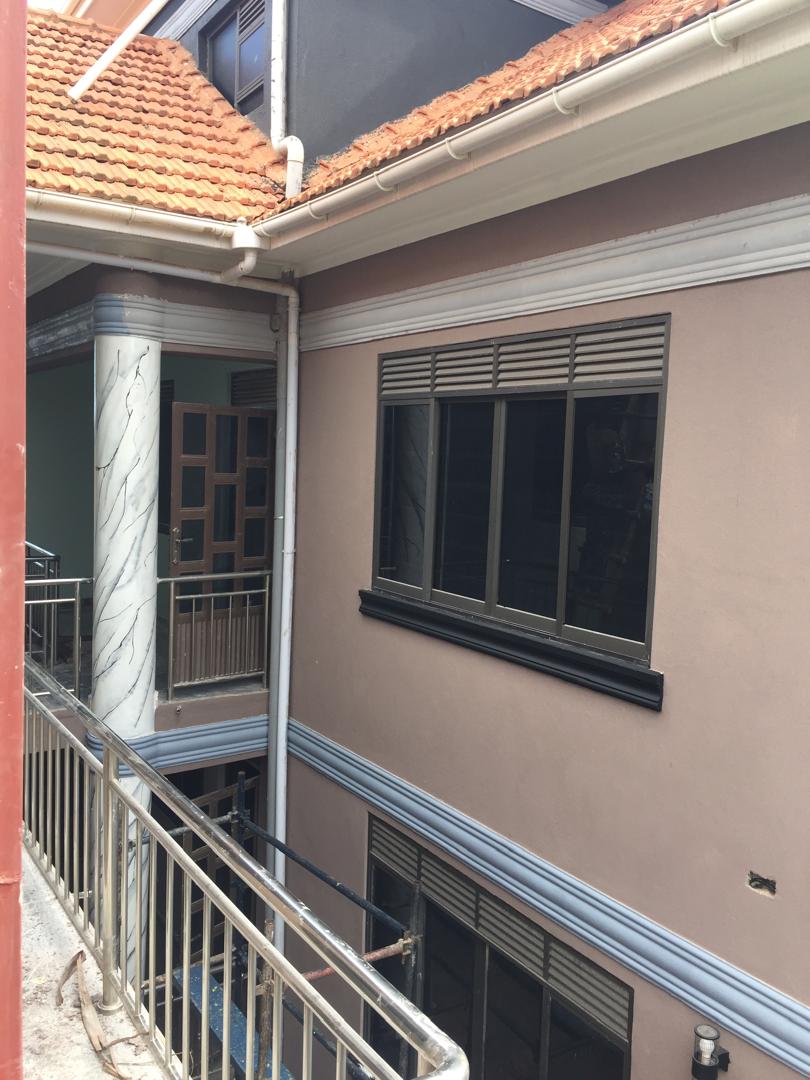 Two-storey house exterior finished in soft mauve with a marble-effect balcony column