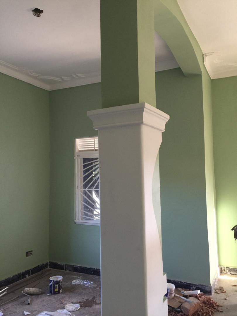 Sage green living room interior with a white archway column and ceiling cornice