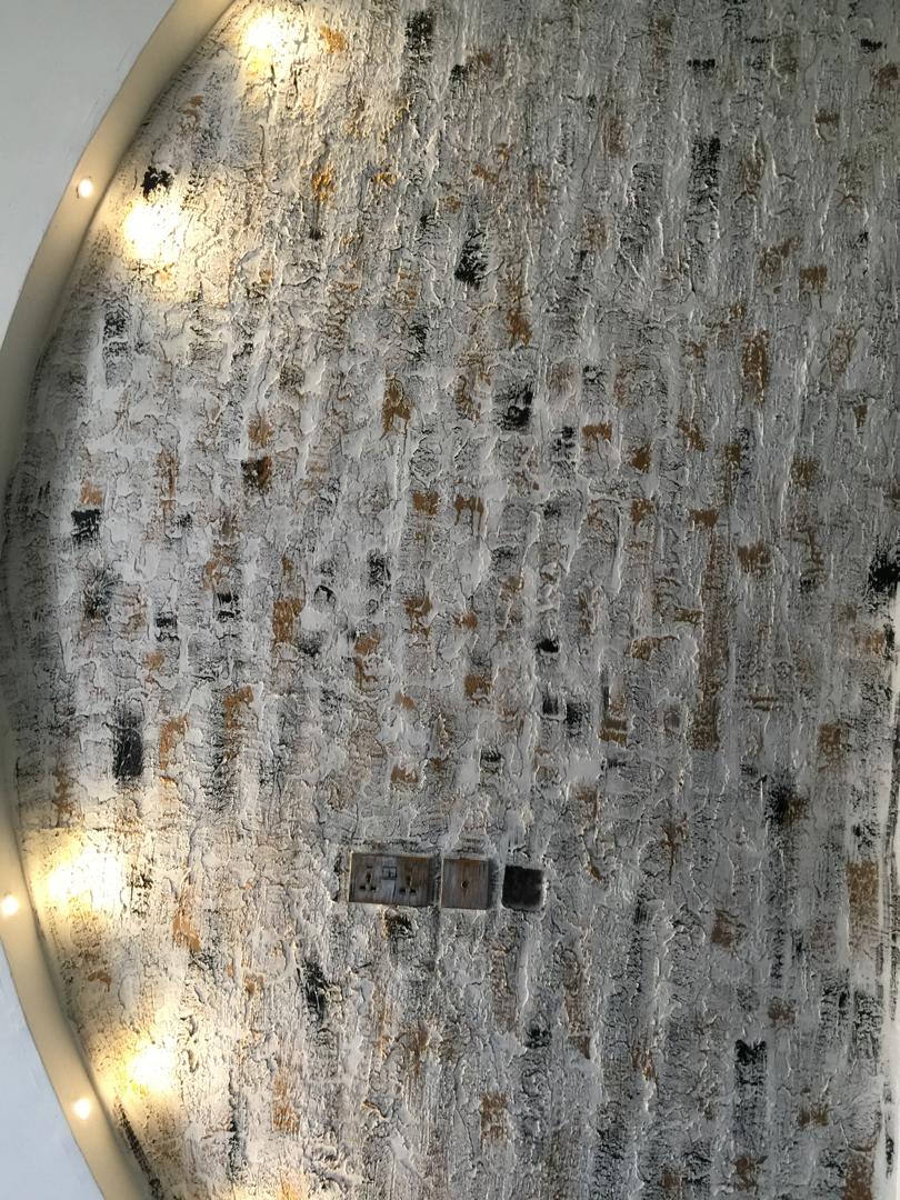 Close-up of a hand-applied textured wall finish in cream, black, and gold tones